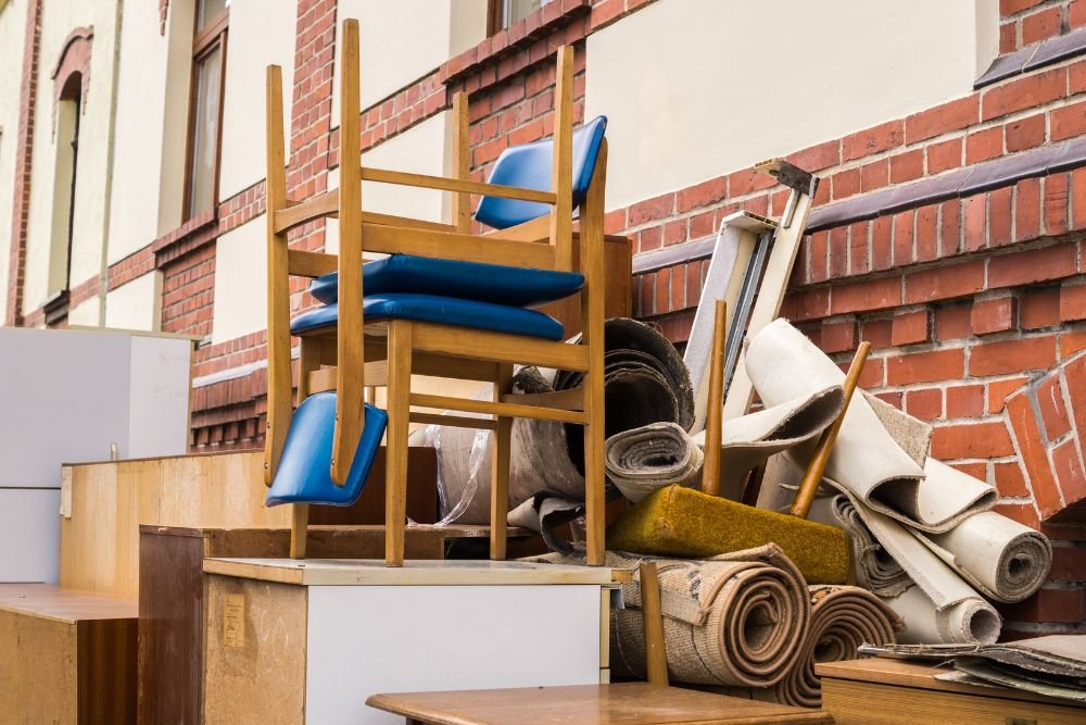 Discarded furniture and chairs piled in front of a brick building, showcasing a clean-out service in Springfield, IL.